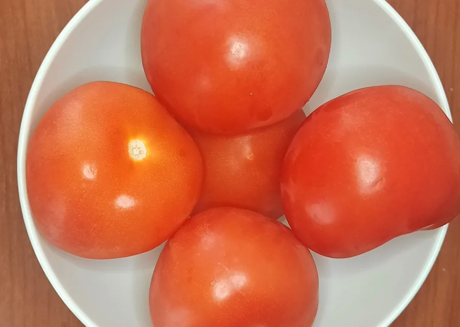 Cinco jitomates en un tazón blanco